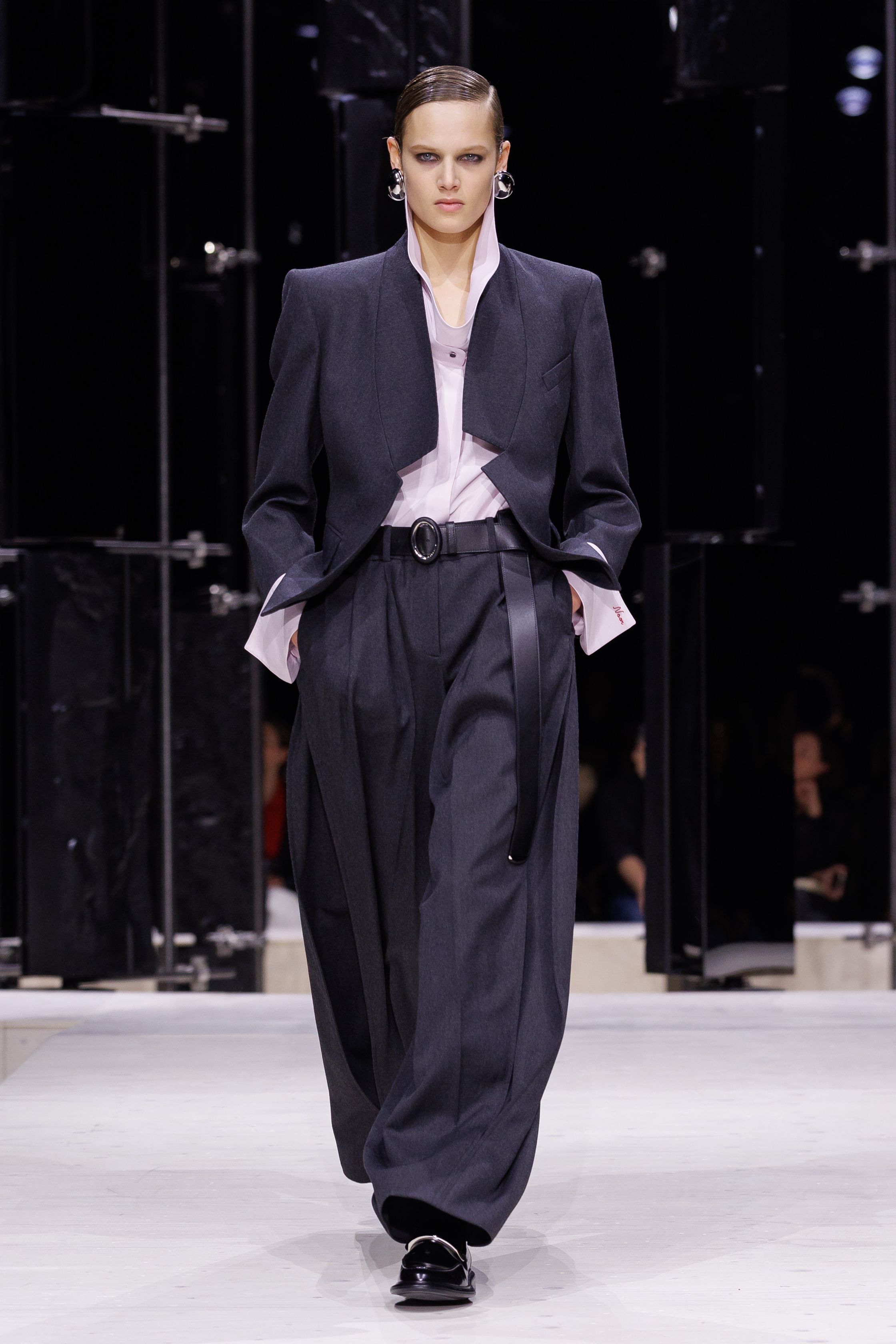 Givenchy 2026秋冬在现代建筑空间中呈现一场充满戏剧性的时装叙事：雕塑式西装、亮色斗篷、结构礼服与夸张装饰共同构建品牌标志性的高级时装气质。蓝色、红色与黄色的高饱和色彩与黑白经典形成鲜明对比，服装通过立体剪裁与夸张廓形展现出强烈视觉张力。整场系列在优雅与戏剧之间取得平衡，展现现代高级时装的力量-顽石频道趋势研究